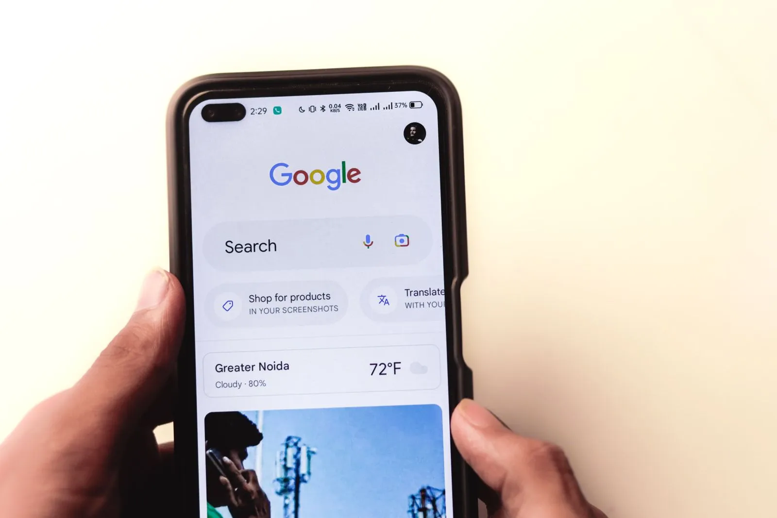 Mains tenant un smartphone affichant la page de recherche Google sur fond clair