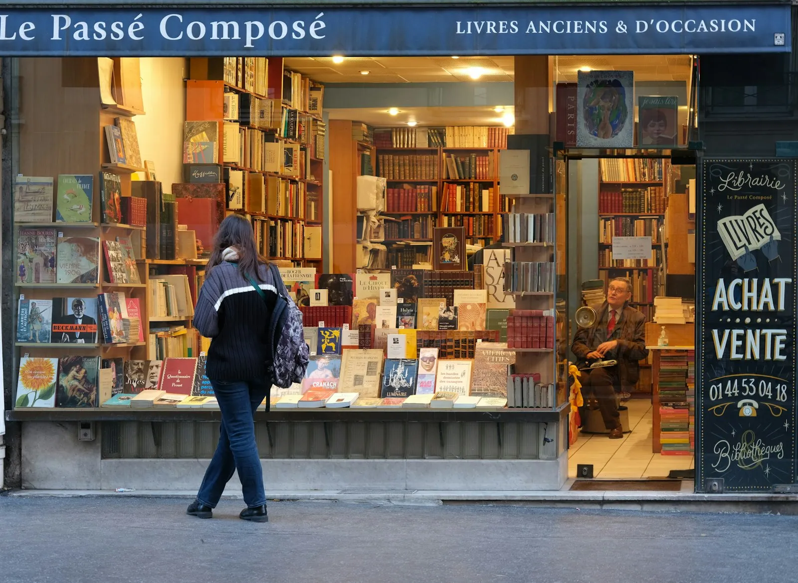 Passante devant la vitrine d'une librairie de quartier parisienne